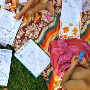 Děti na dece tvoří plakáty Caromat Zločinci hra pro děti k tisku, kreslí a lepí části obličejů.