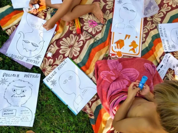 Děti na dece tvoří plakáty Caromat Zločinci hra pro děti k tisku, kreslí a lepí části obličejů.